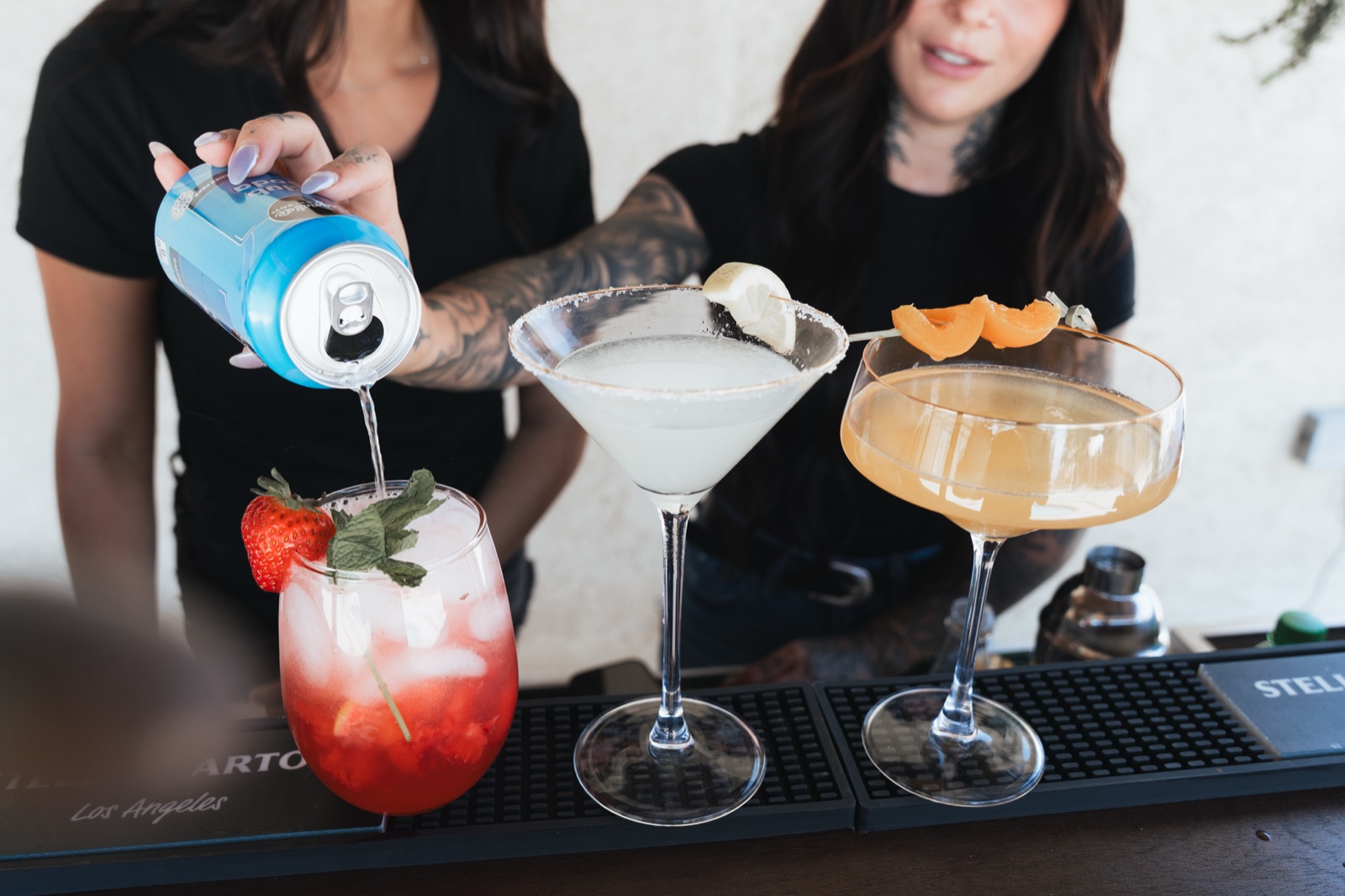 Three finished cocktails with fresh garnishes lined up on the bar