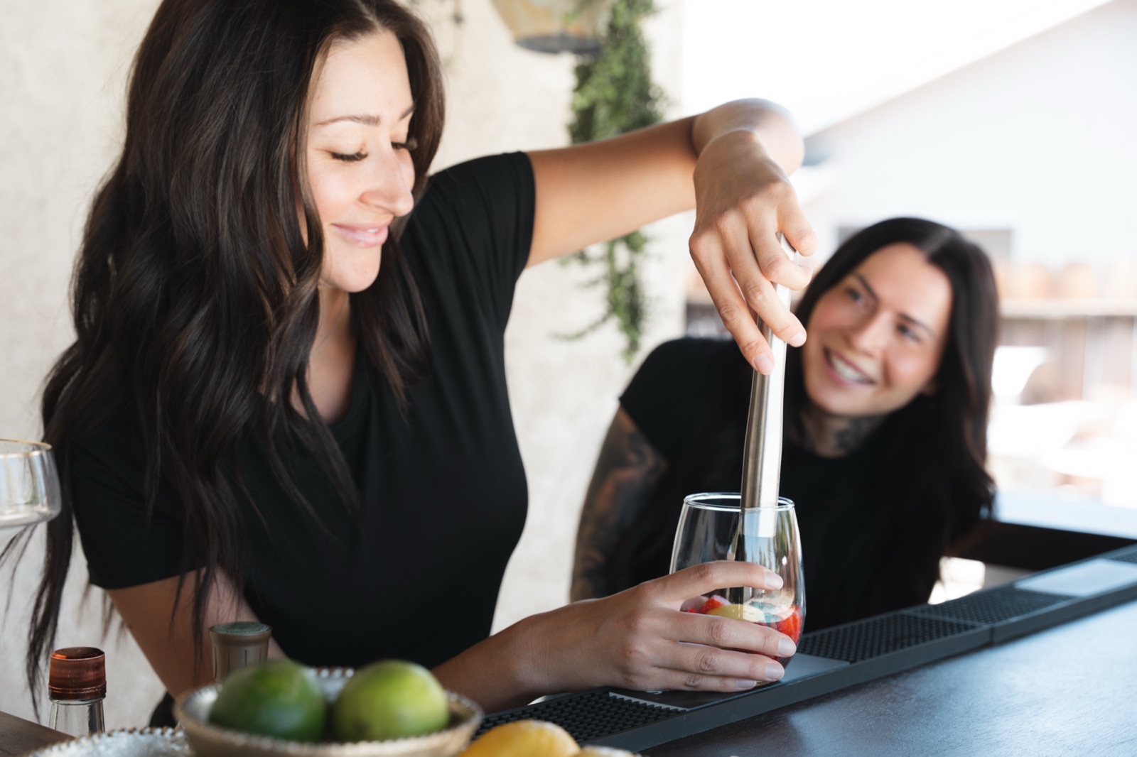 Bartender muddling fresh strawberries while the other looks on
