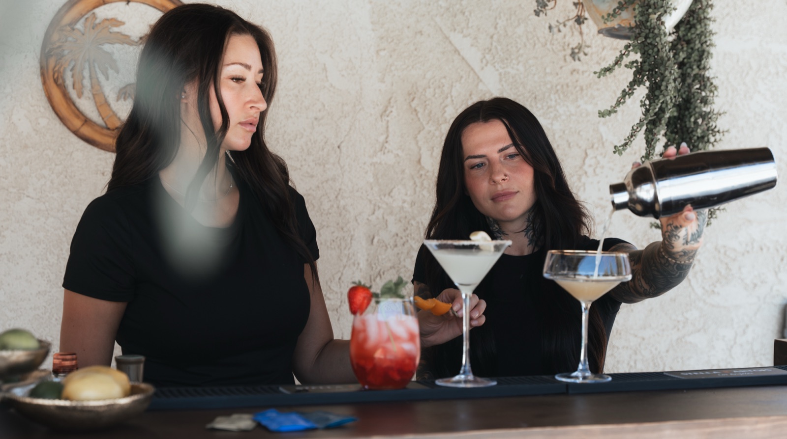Bartender pouring from a shaker with finished cocktails lined up
